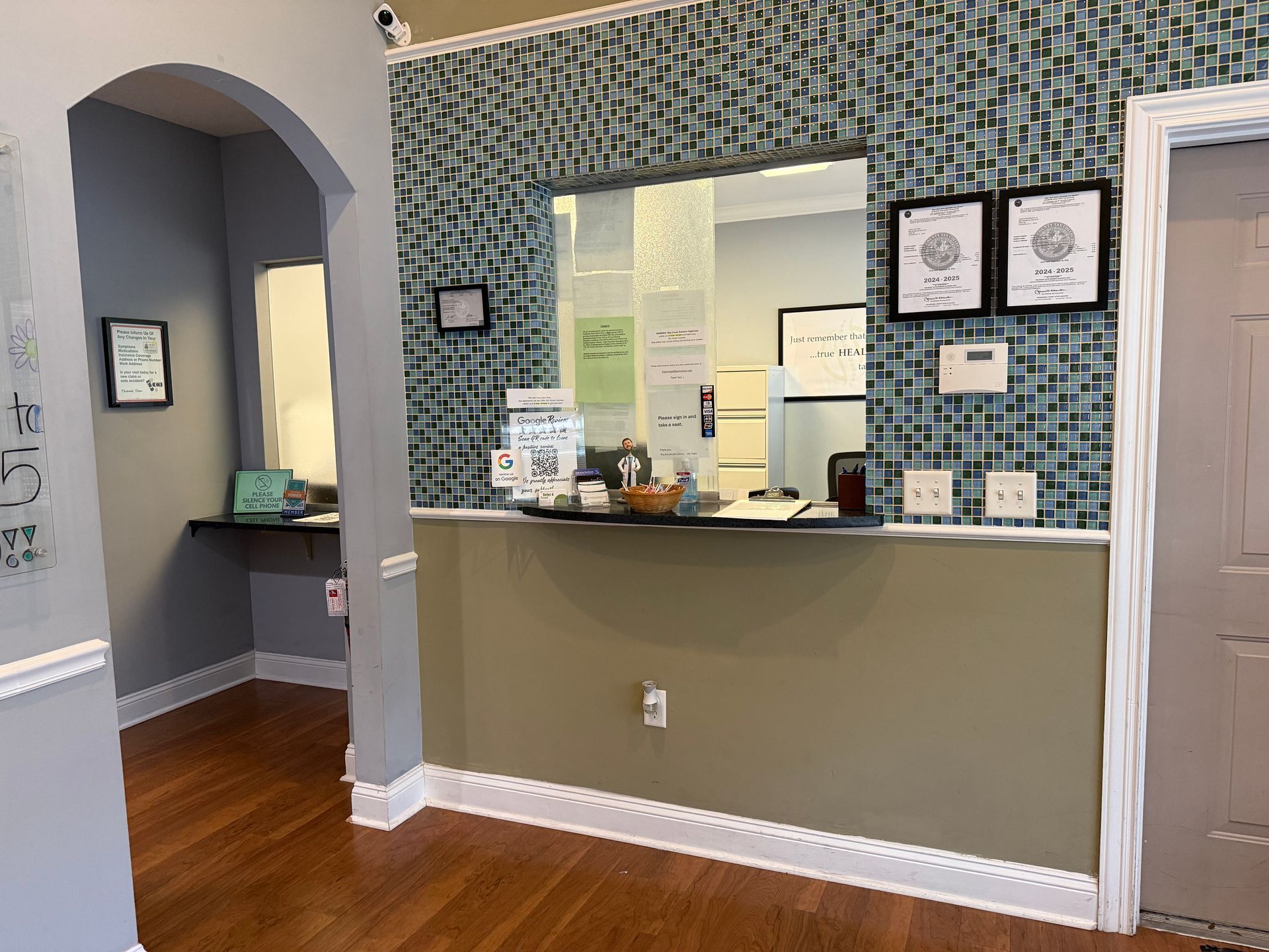 Empty reception area with patterned wallpaper, gray counter, and wood floor