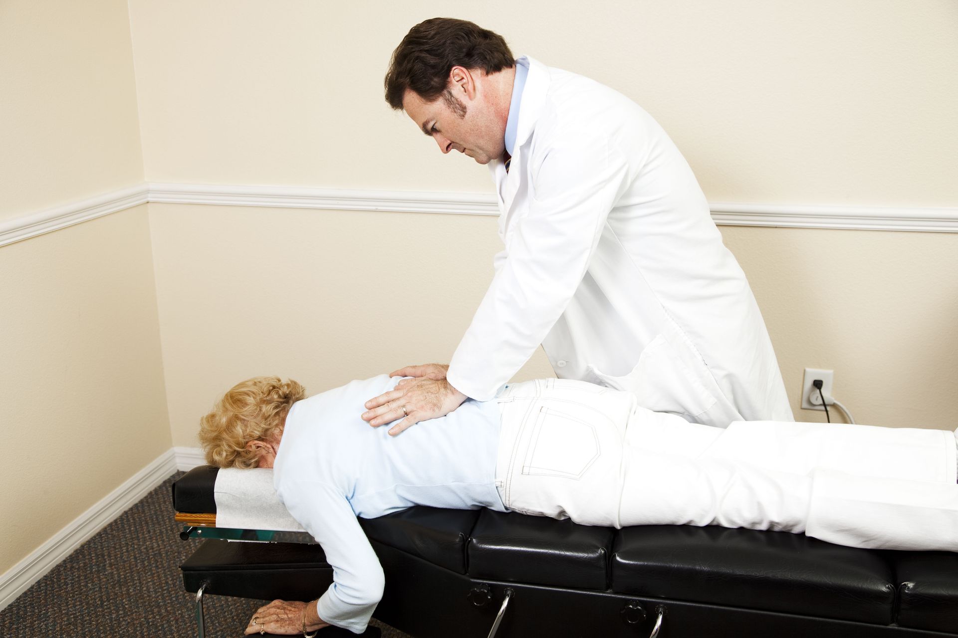 Chiropractor adjusting a patient lying face down on a treatment table