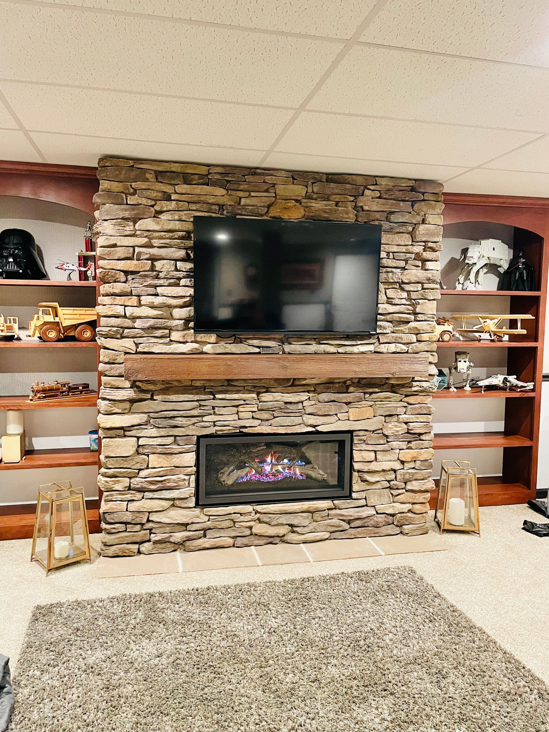 Stone fireplace wall with mounted TV, electric fire, and built-in shelves in a cozy living room