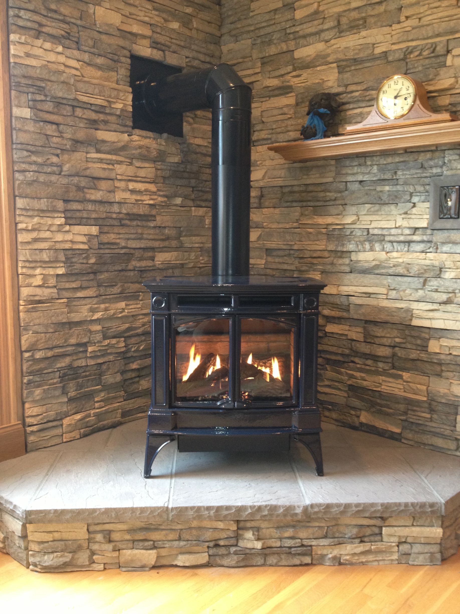 Wood-burning stove with a lit fire on a stone hearth in a rustic room