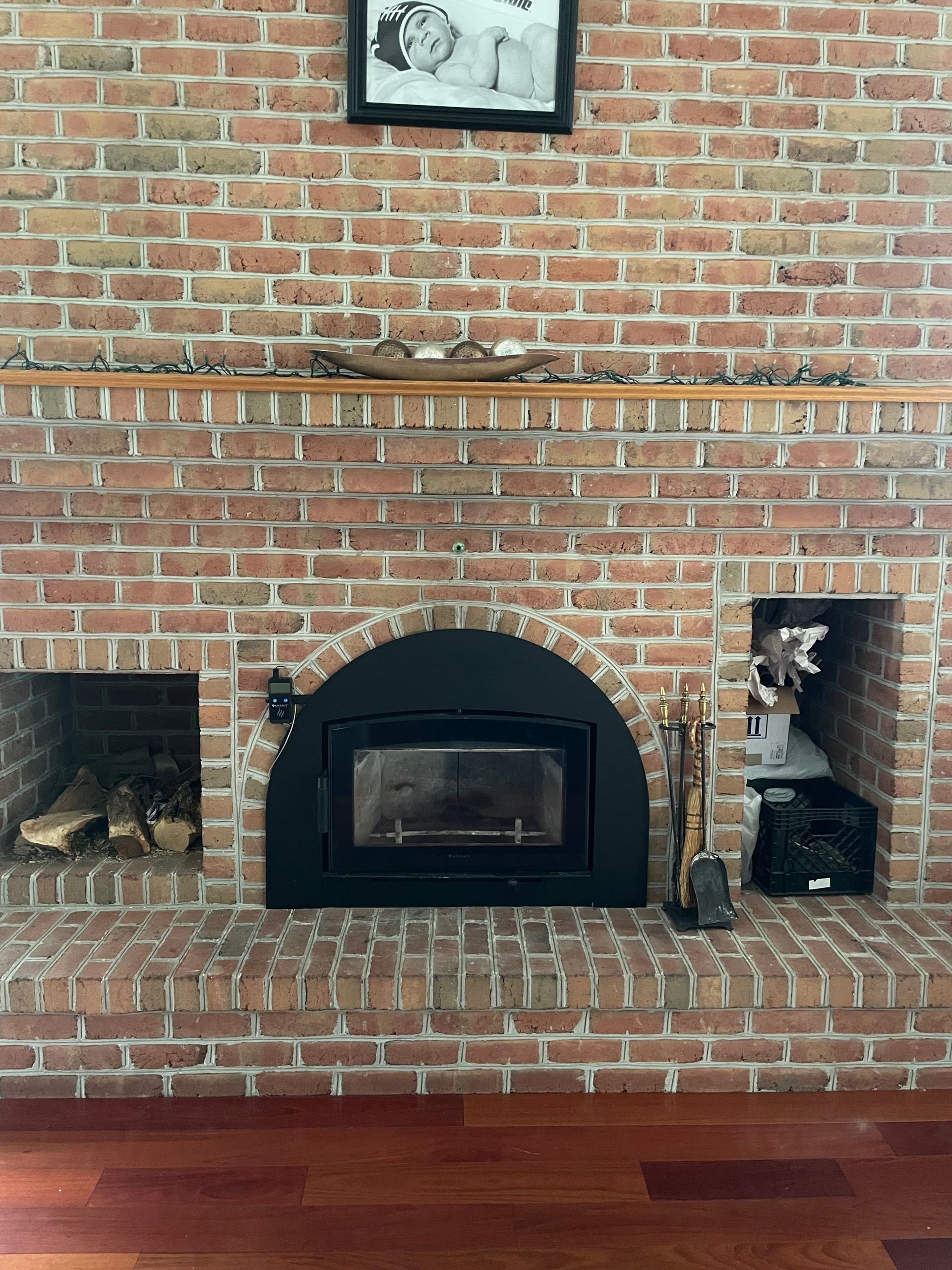 Brick fireplace with black arched insert and decorative niches in a room with wood floors