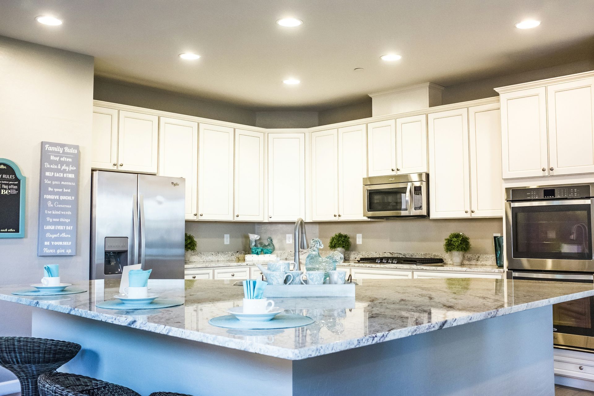a kitchen with white cabinets, granite counter tops, stainless steel appliances and a large island