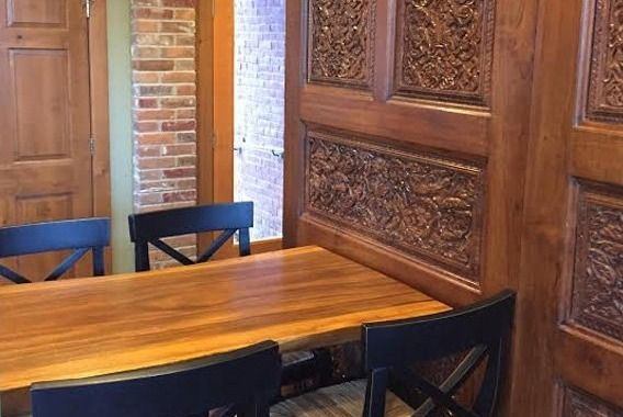 Wooden conference table with dark chairs in a room with brick and carved wood walls