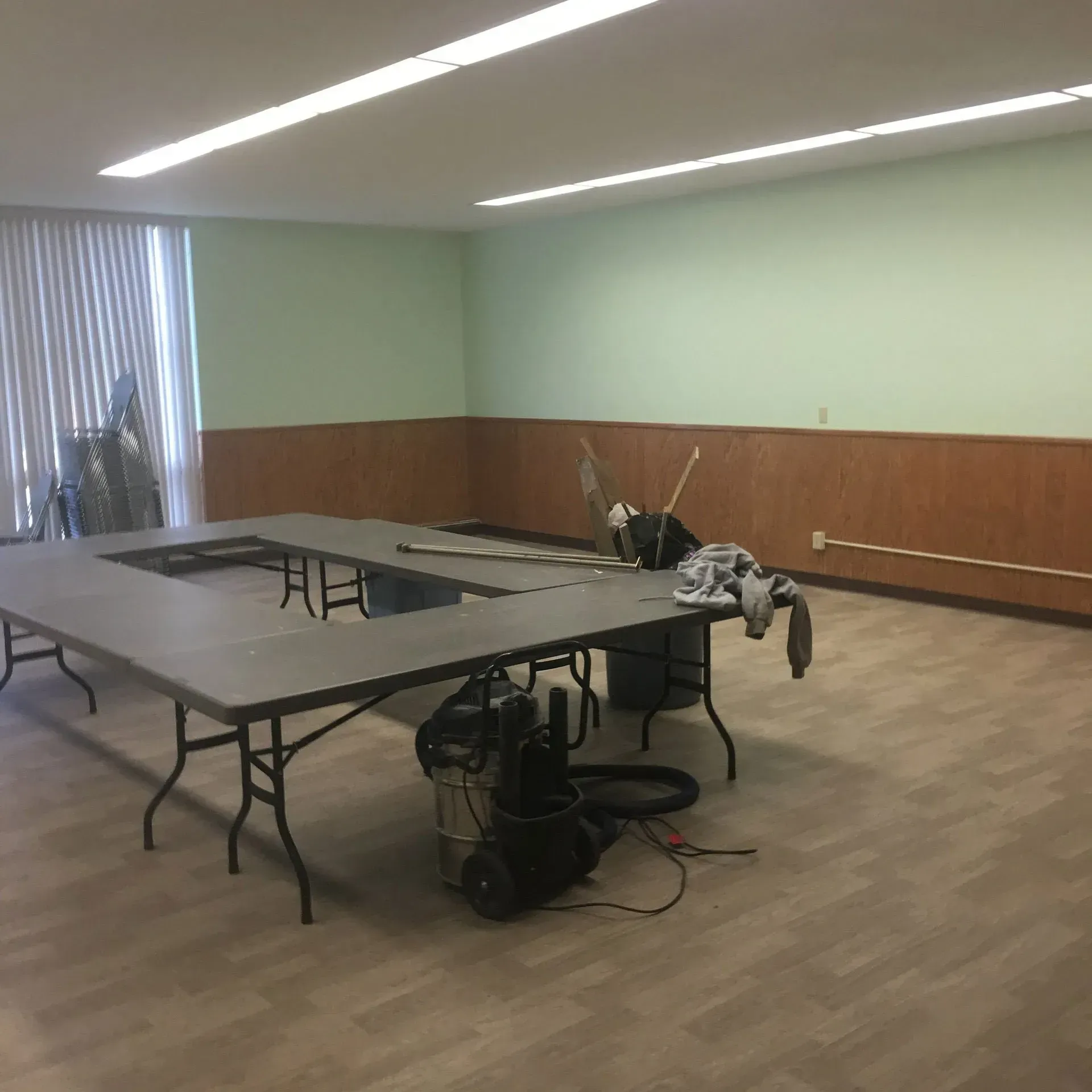 Empty conference room with a large folding table, chairs, and equipment on the floor near the center.