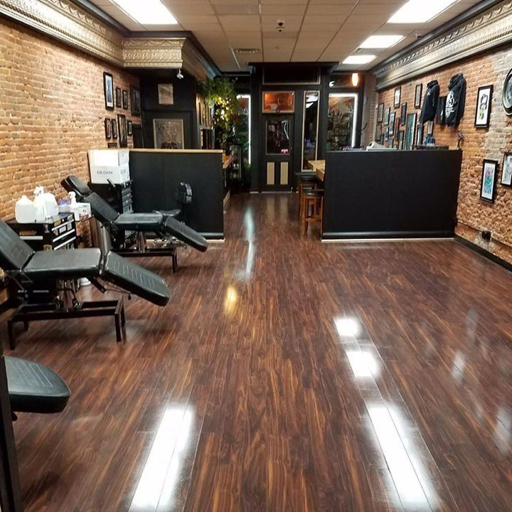 Empty barber shop interior with brick walls, black chairs, and glossy wood floors