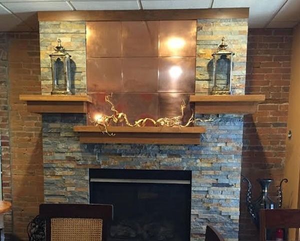 Brick fireplace with stone surround, two lanterns, and a decorative mantel in a living room.