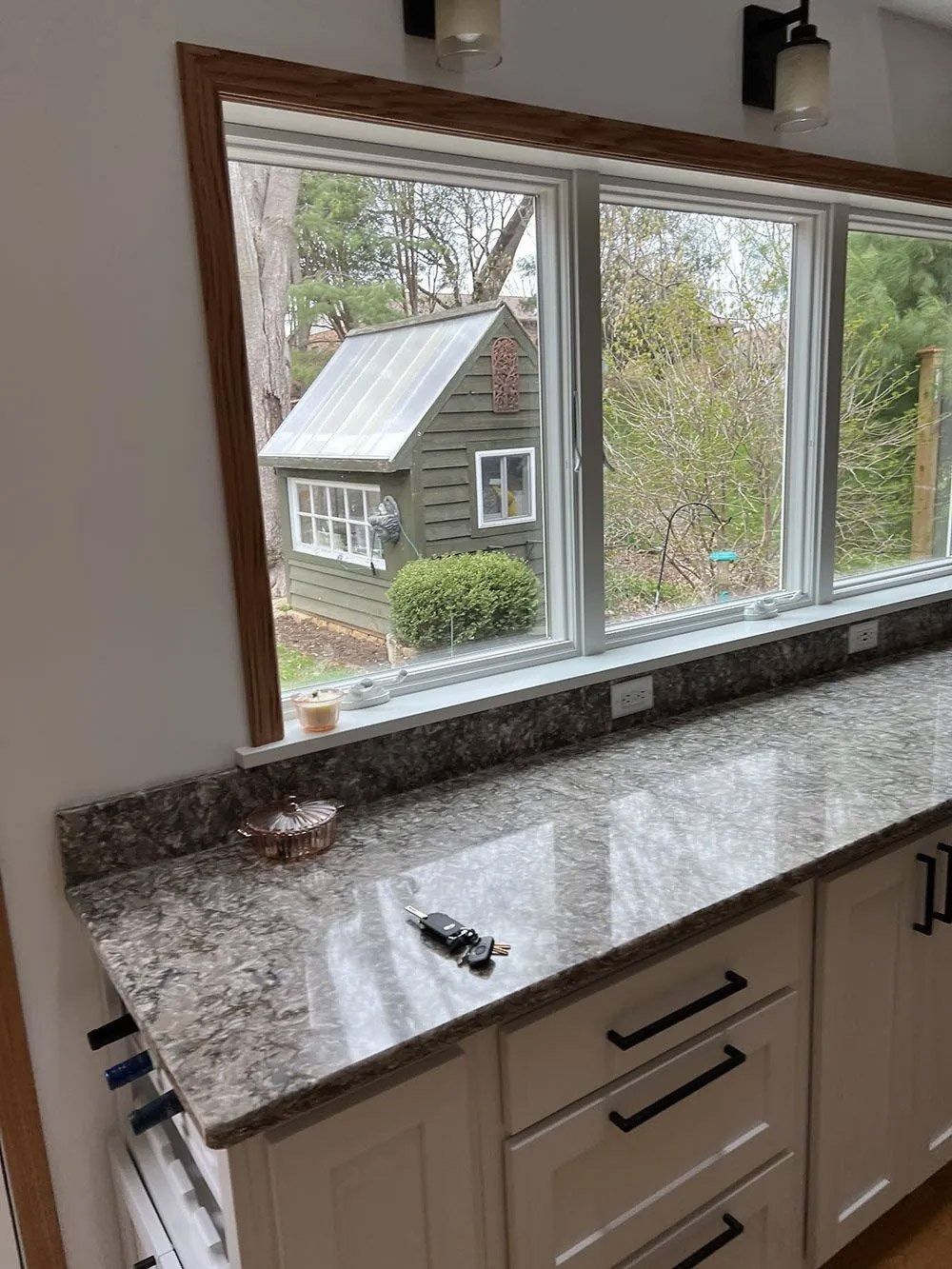 Kitchen window over granite countertop, with a view of a house outside.