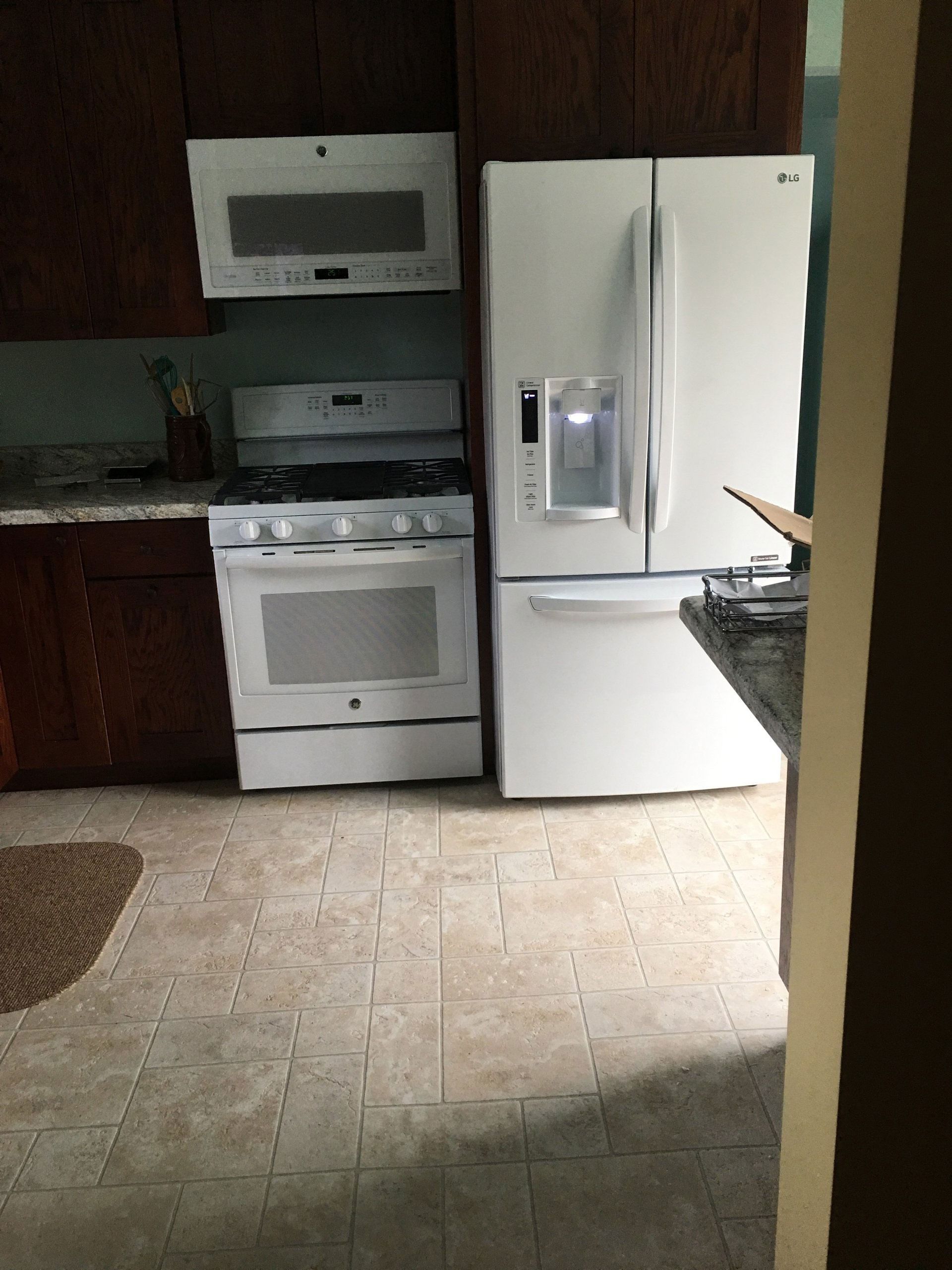 Kitchen with white refrigerator, stove, microwave, and dark wood cabinets.