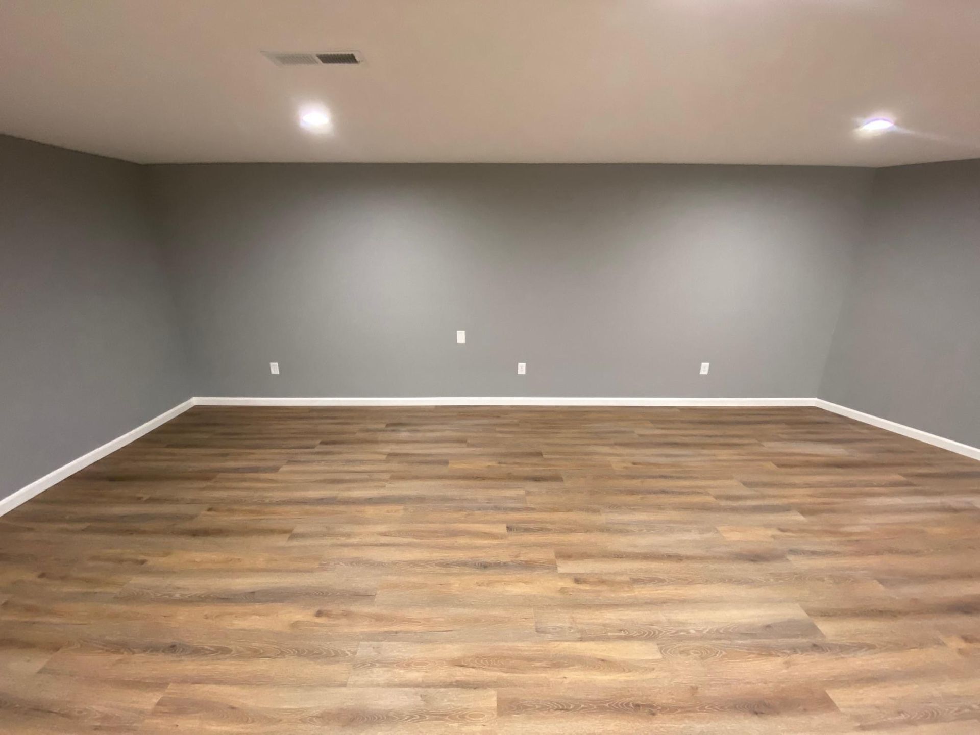 Empty room with gray walls, wood floor, and recessed ceiling lights