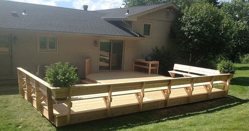 Backyard wooden accessibility ramp and deck beside a house