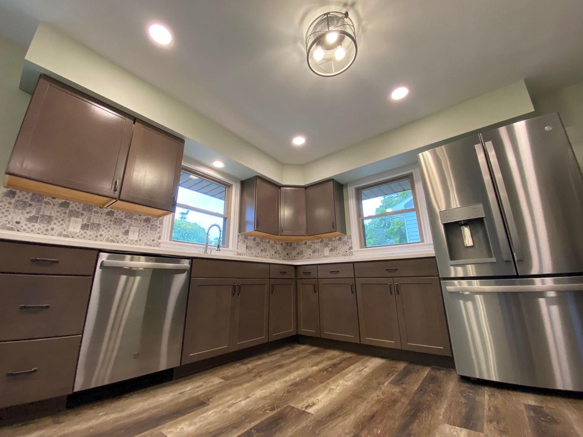 Modern kitchen with stainless steel appliances, wood cabinets, and wood-look flooring