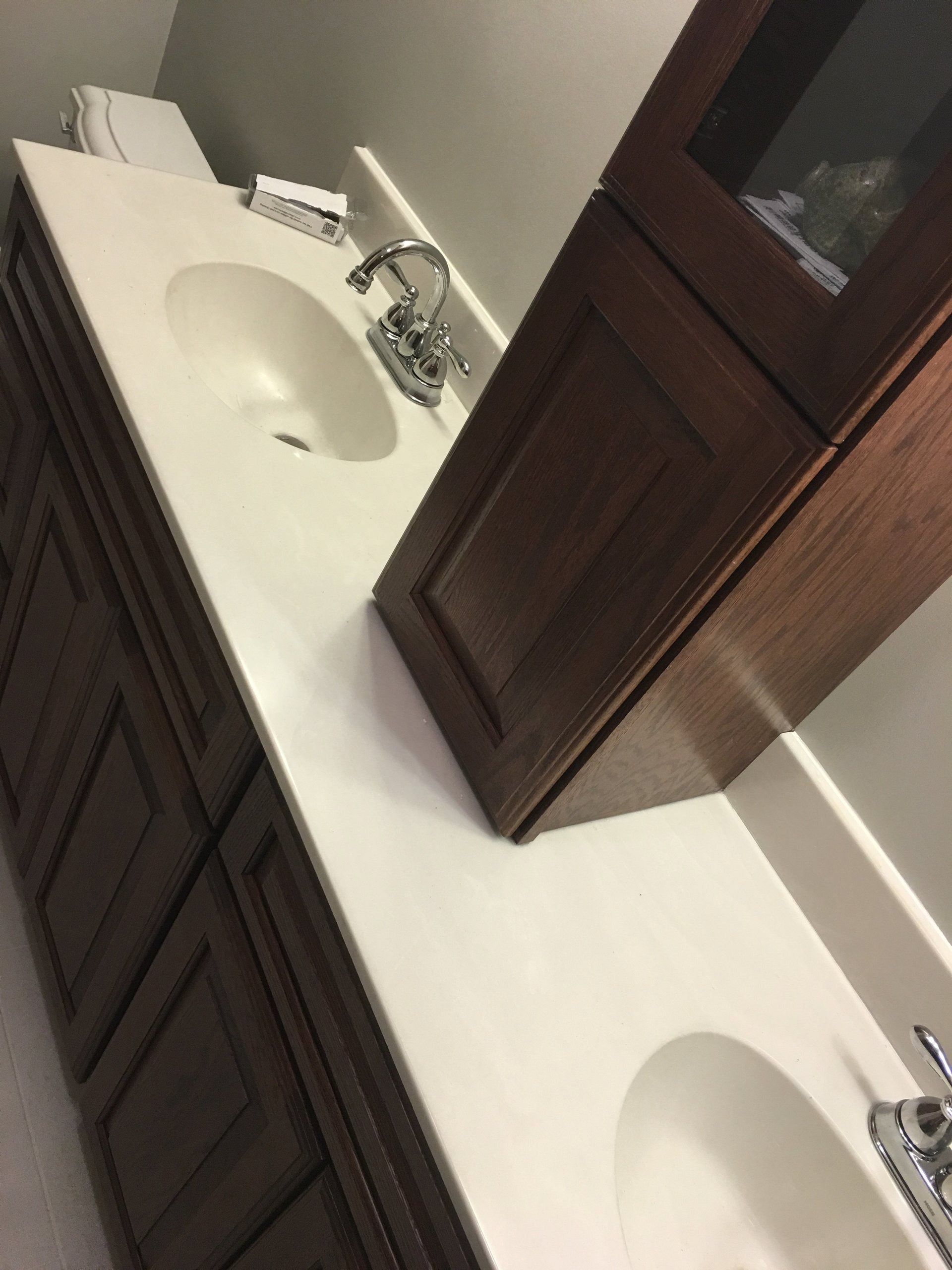 Two white bathroom sinks with dark wood cabinets and a large mirror above the counter.