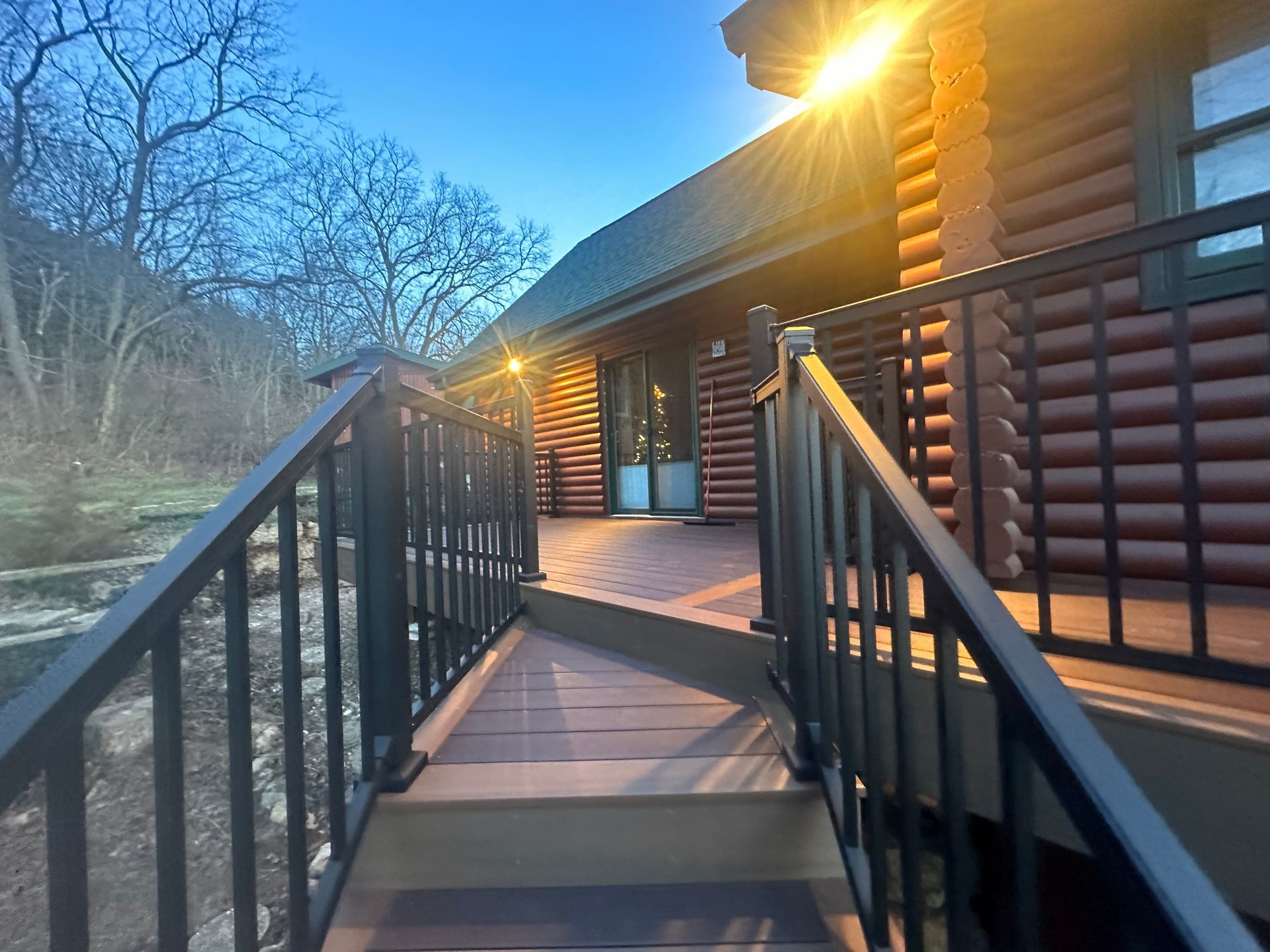 Log cabin deck at sunset with black railings and mountain view