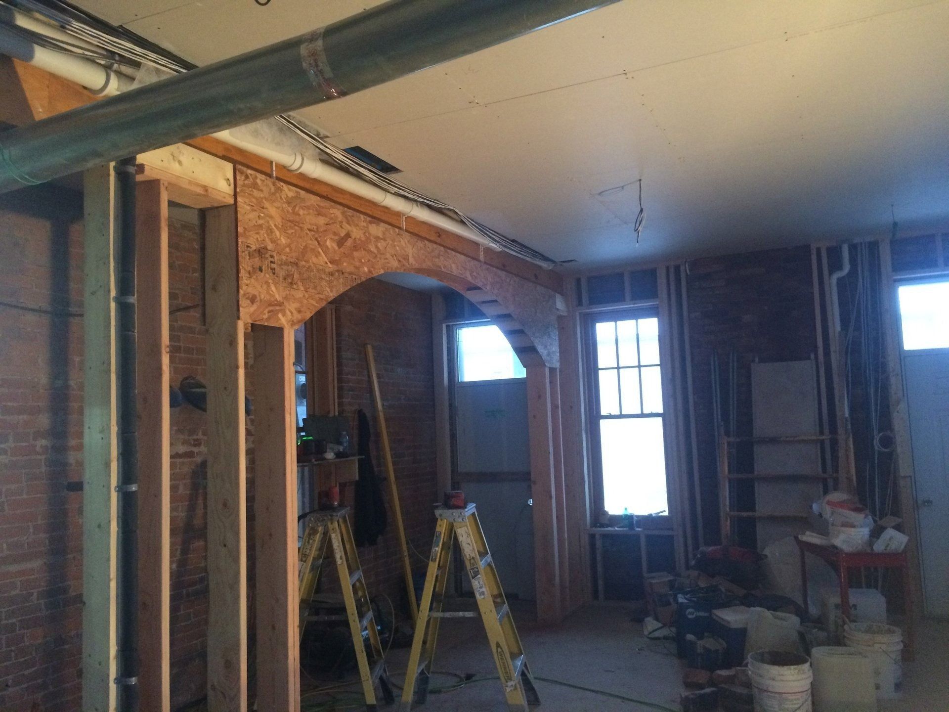 Renovation site with exposed brick walls, ladders, and construction materials inside a room