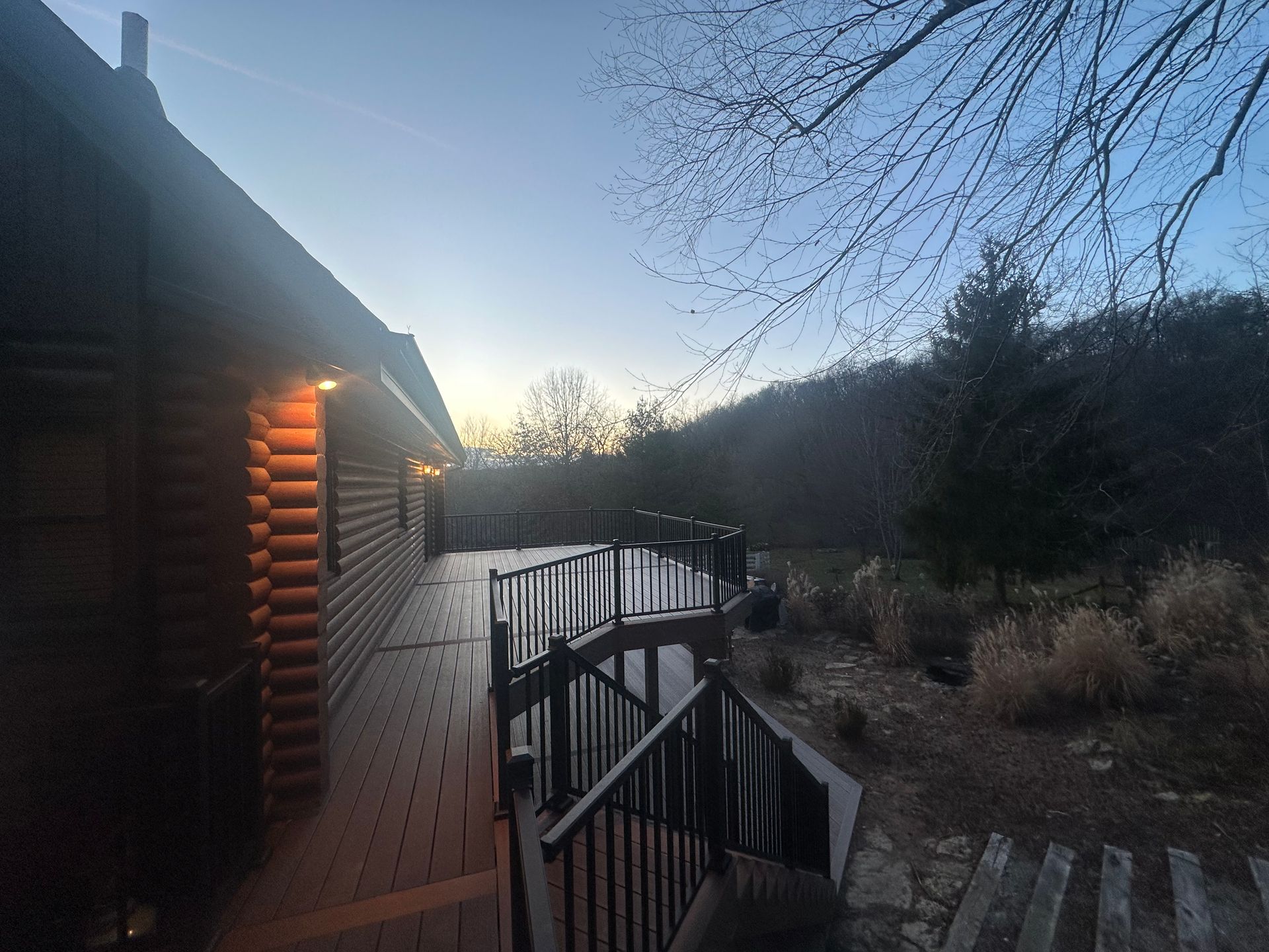 Log cabin deck at dawn overlooking a misty river and bare trees