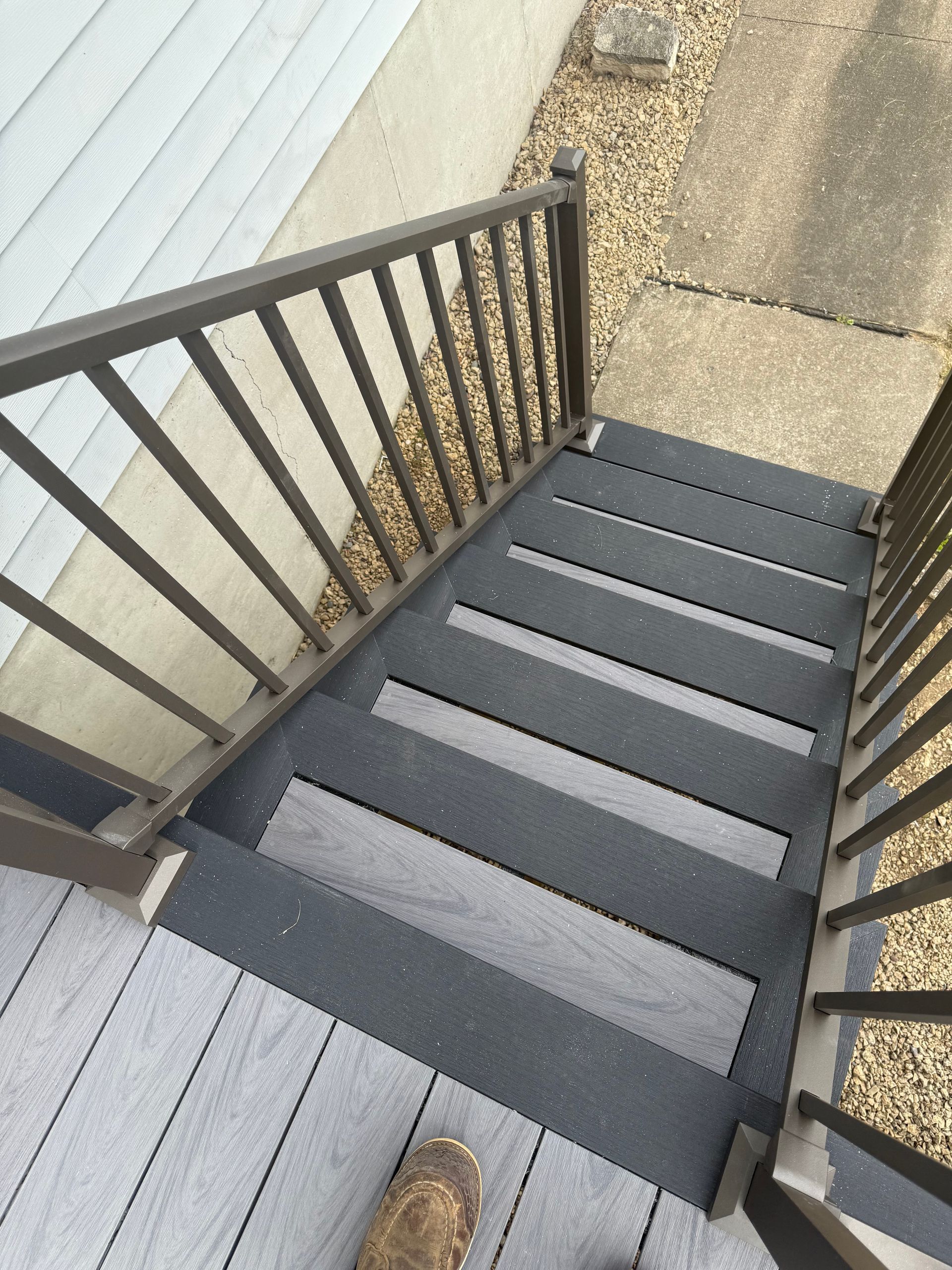 Black outdoor stairs with railings beside a house, viewed from the top.