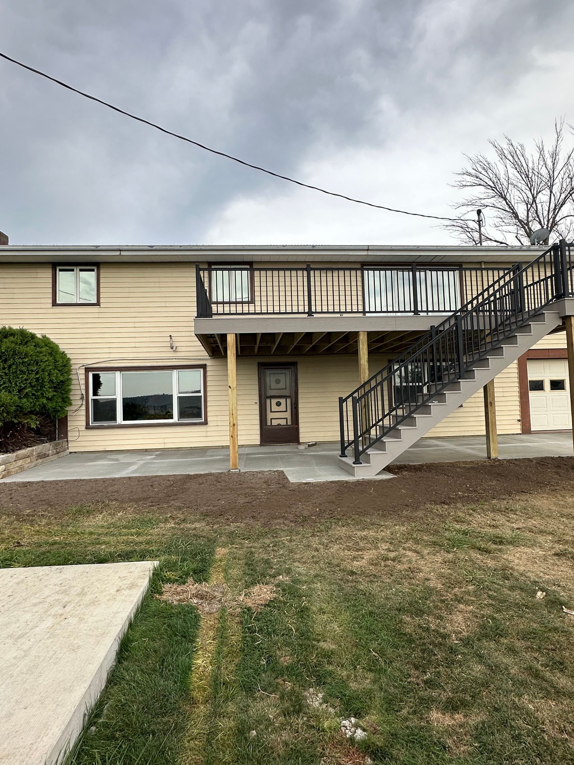 Apartment building exterior with balcony, staircase, and cloudy sky