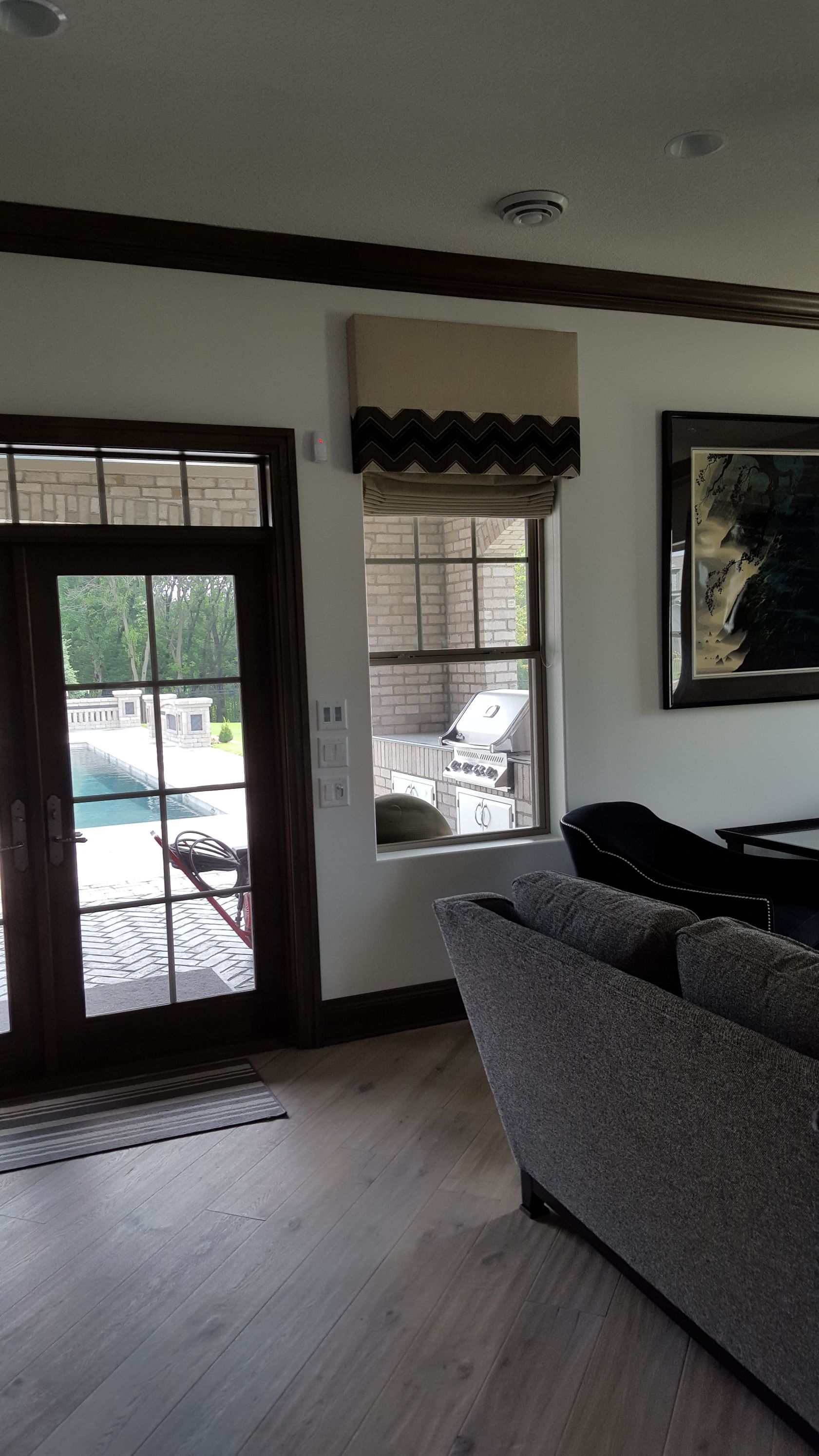 A living room with a couch and a window with a view of a pool.
