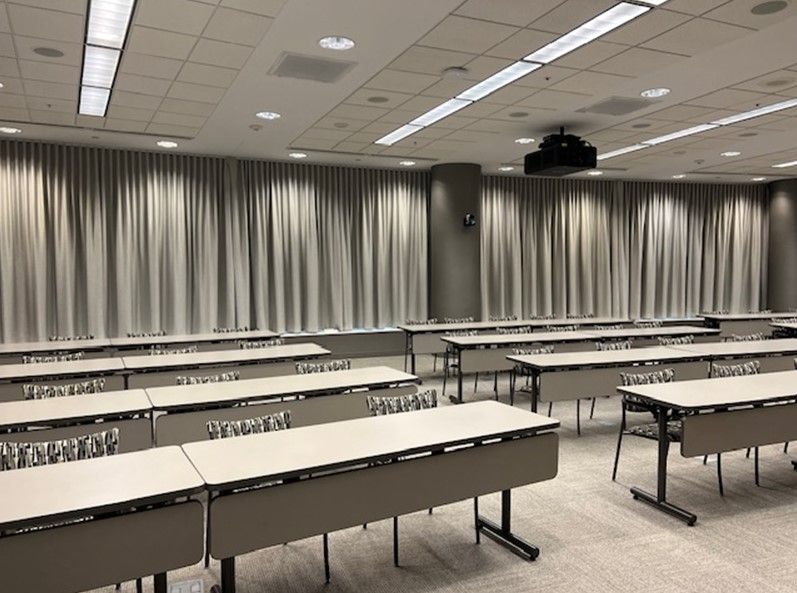An empty conference room with tables and chairs and curtains