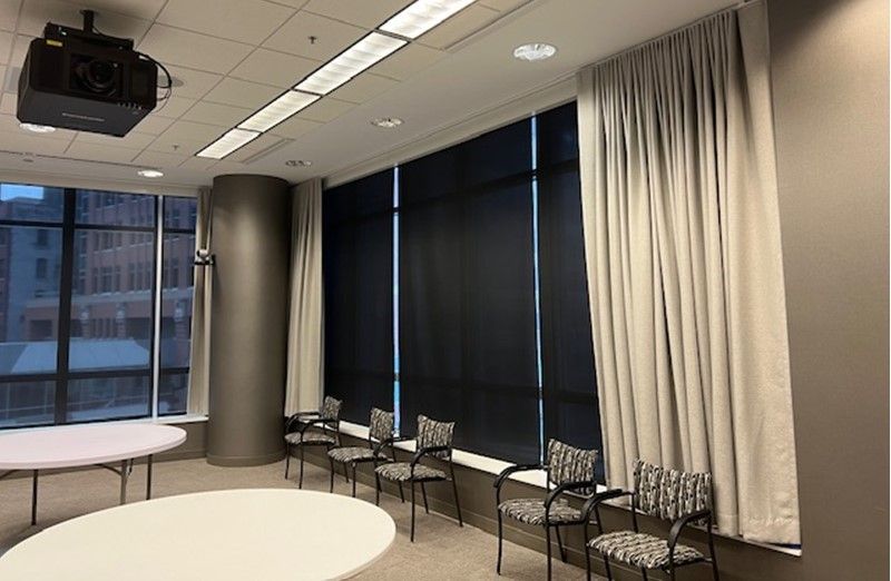 A room with tables and chairs and a projector on the ceiling.