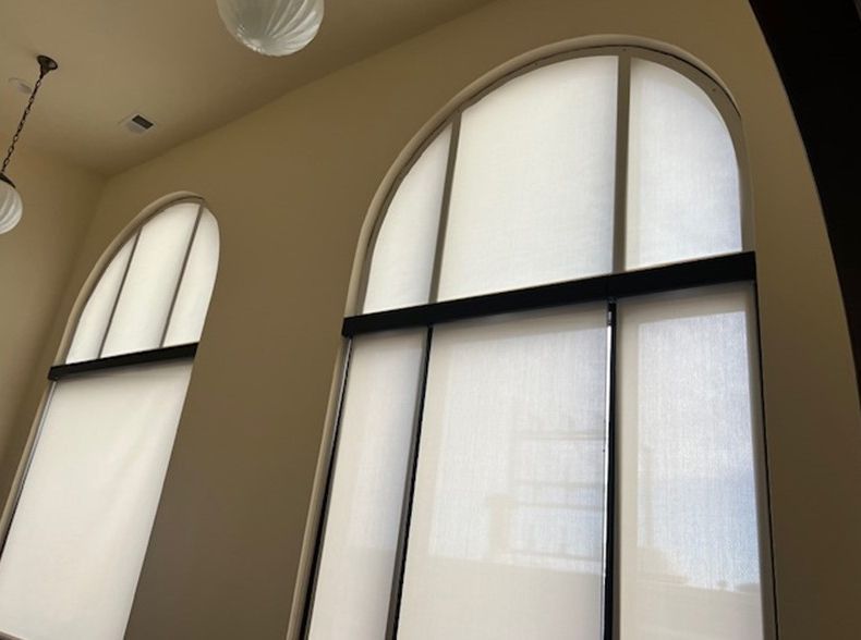 Two arched windows with white blinds in a room
