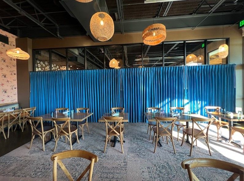 A restaurant with tables and chairs and blue curtains.
