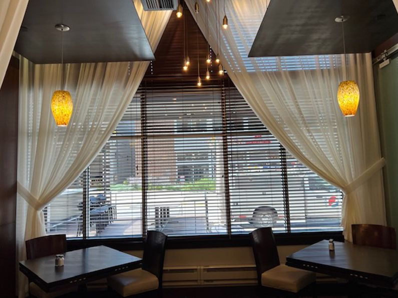 A restaurant with tables and chairs in front of a window with blinds