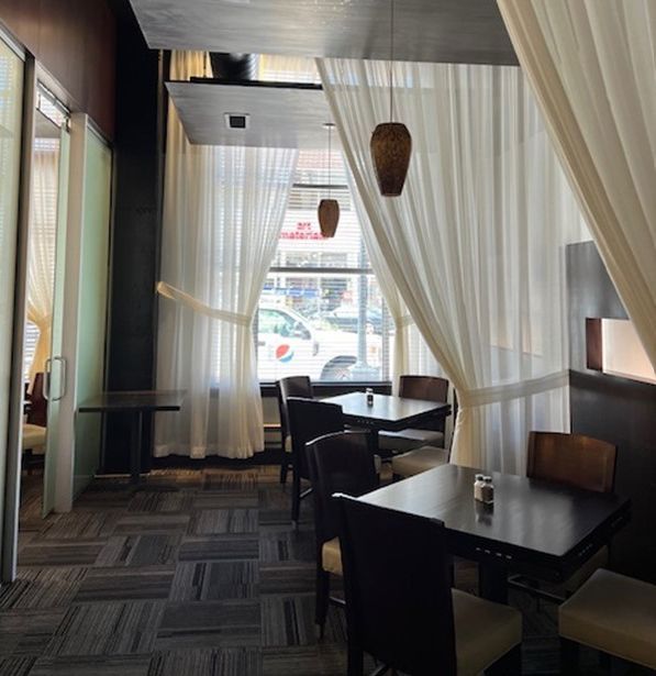 A restaurant with tables and chairs and curtains hanging from the ceiling