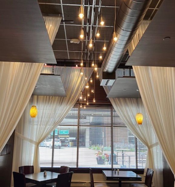 A restaurant with tables and chairs and curtains hanging from the ceiling