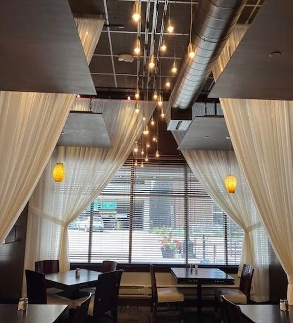 A restaurant with white curtains and tables and chairs