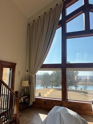Tall living room with floor-to-ceiling windows, beige curtains, and a snowy landscape outside.