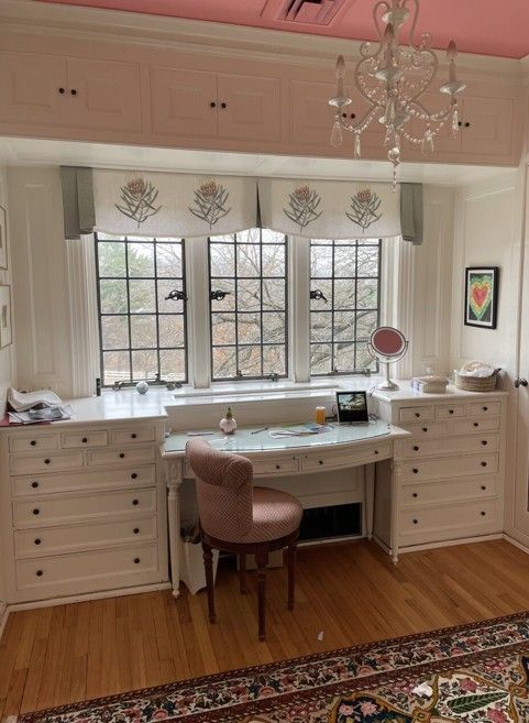 Bright white home office with large window, built-in desk, pink chair, and patterned rug