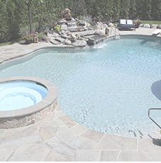 Swimming pool with waterfall, hot tub, and patio.