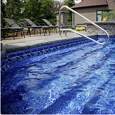 Blue tiled pool with steps and stainless steel handrail, outdoor setting.