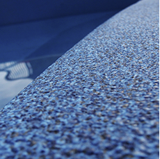 Blue textured pool edge with water and sunlight reflection.