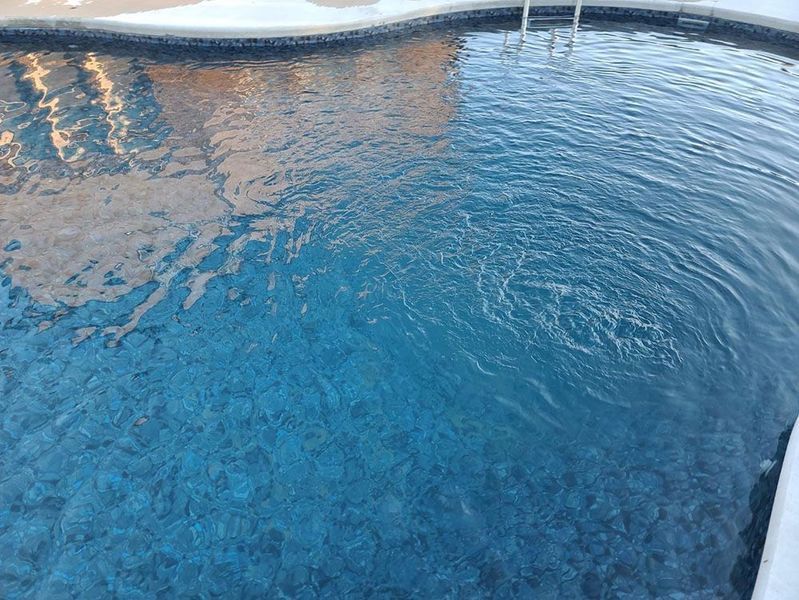 Pool of clear blue water with visible ripples and tile border.