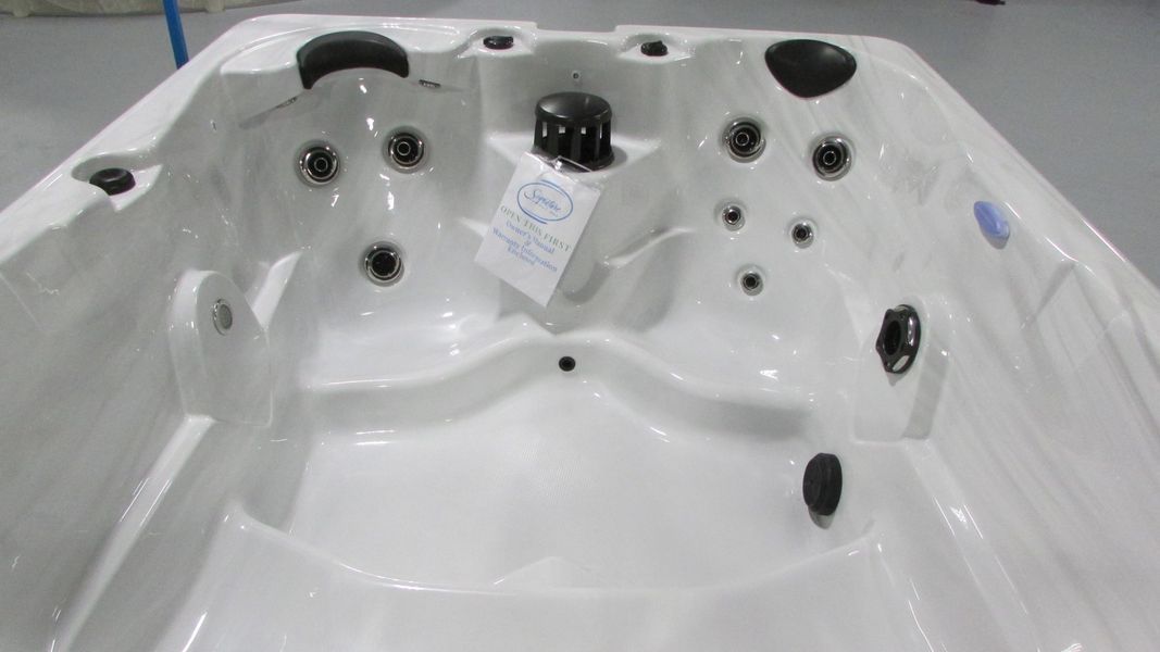White rectangular hot tub with various jets and a central control panel.