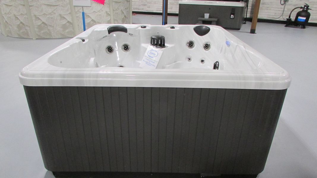 Hot tub with a dark brown exterior and a white interior, on a gray floor.