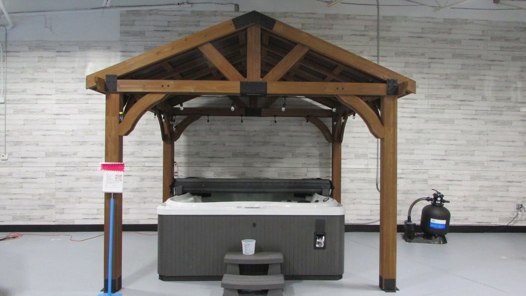 Wooden gazebo with a hot tub inside, in a showroom.