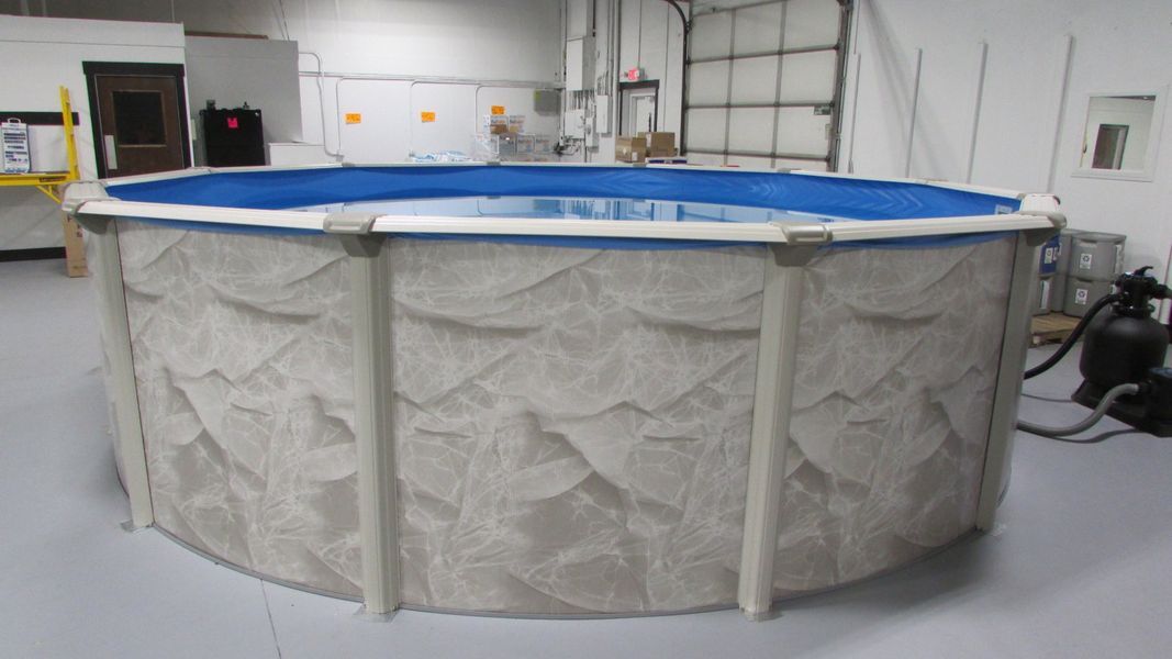 Above-ground, round swimming pool with blue water. Beige textured sides, light gray supports, indoors.