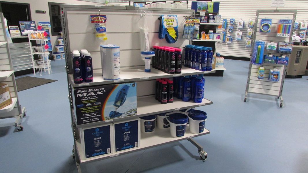 Shelves of pool chemicals and supplies in a retail store. Blue and white products are displayed.