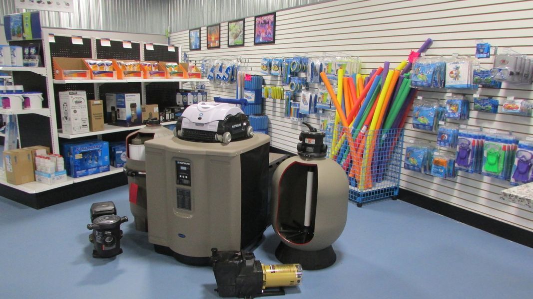 Inside a pool supply store, displays of pool equipment and accessories on blue flooring.