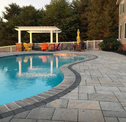 A large swimming pool with a pergola and chairs around it