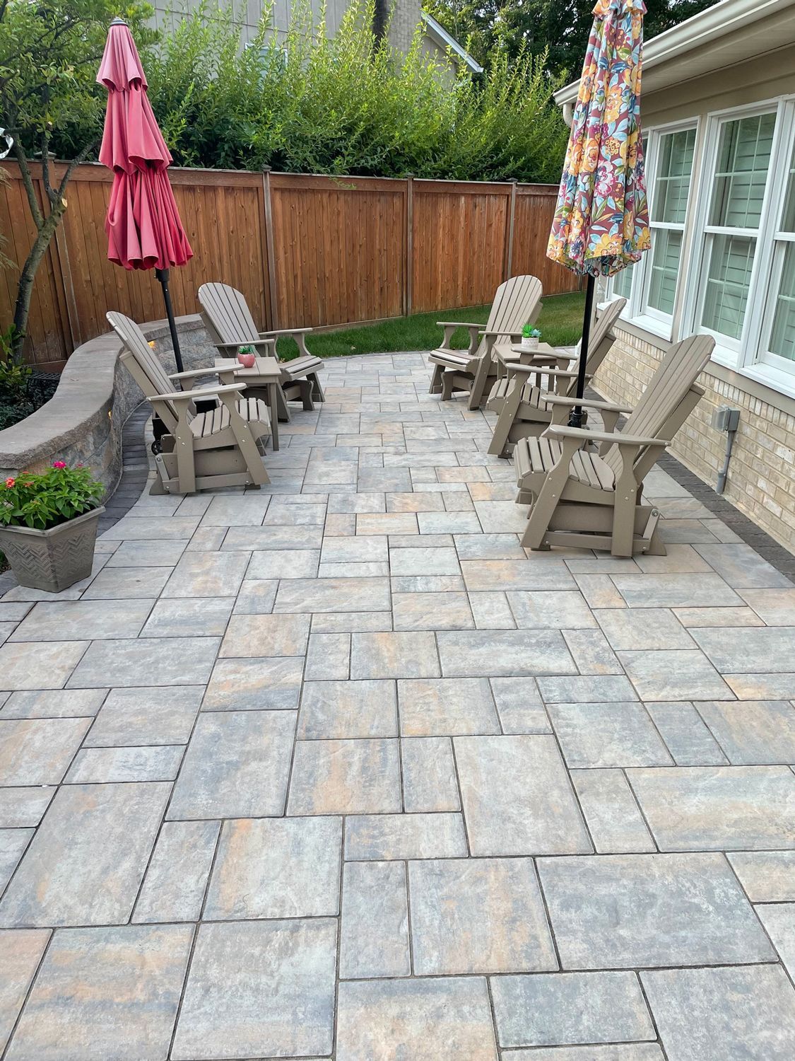 A patio with chairs and umbrellas in front of a house.