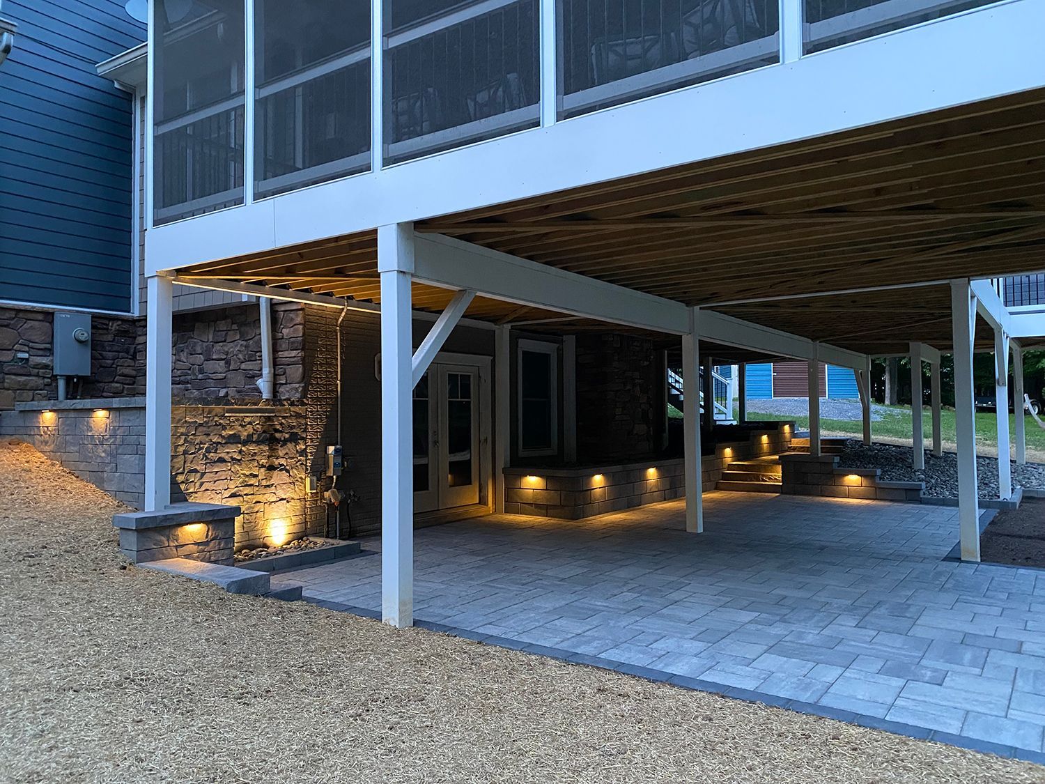 A house with a screened in porch and patio underneath it.