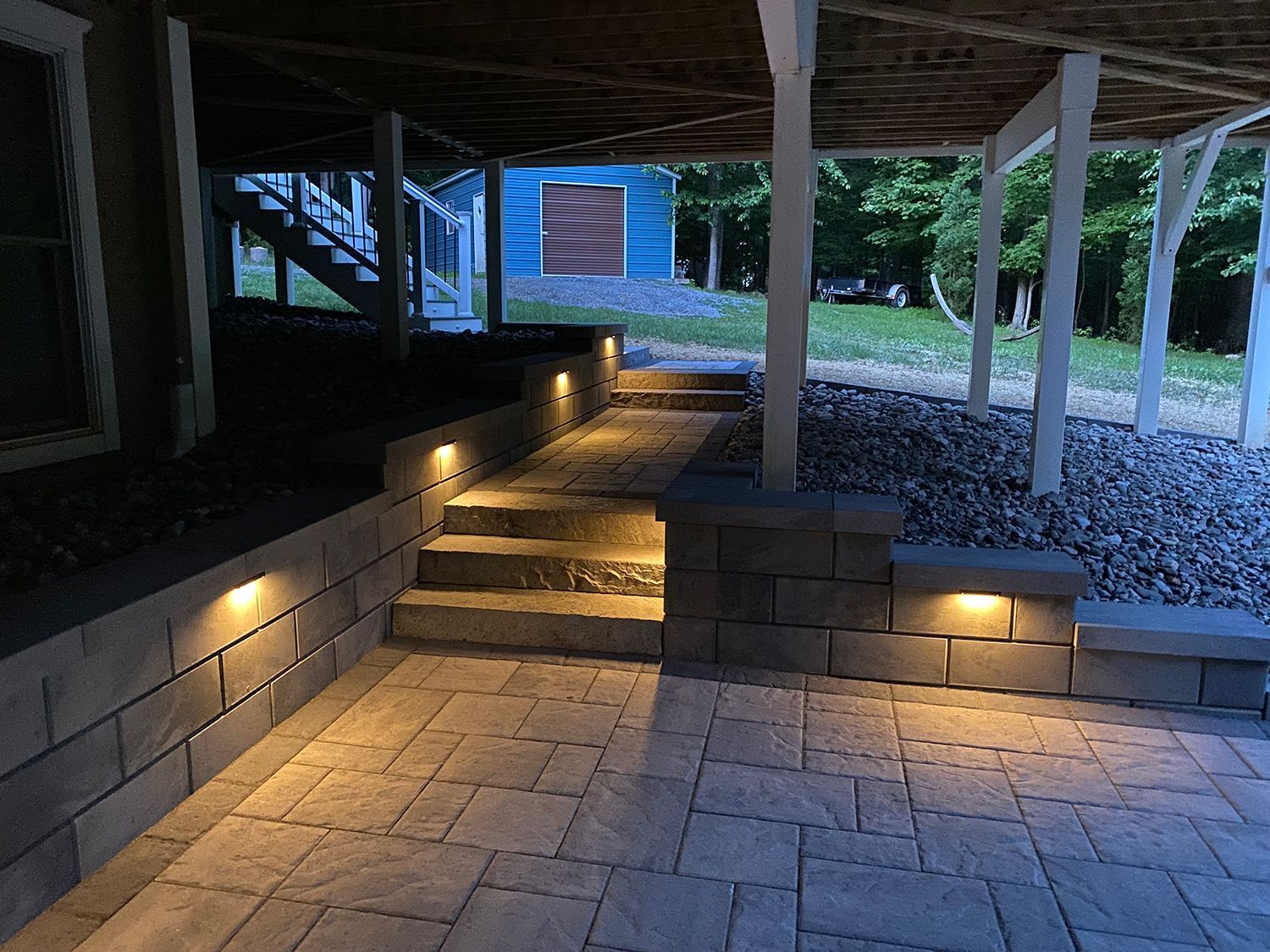 A patio with stairs leading up to a house with lights on the steps.
