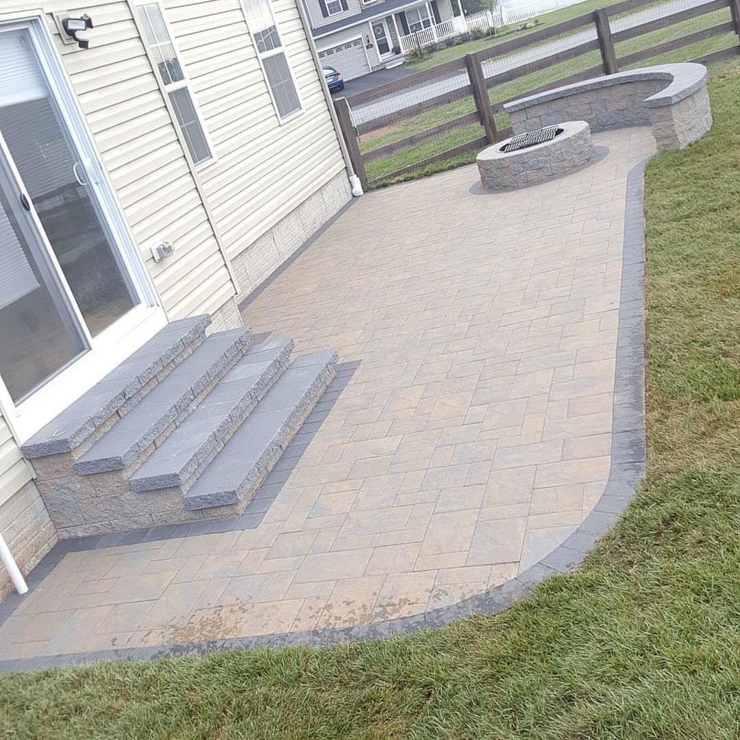 A patio with stairs and a fire pit in front of a house.