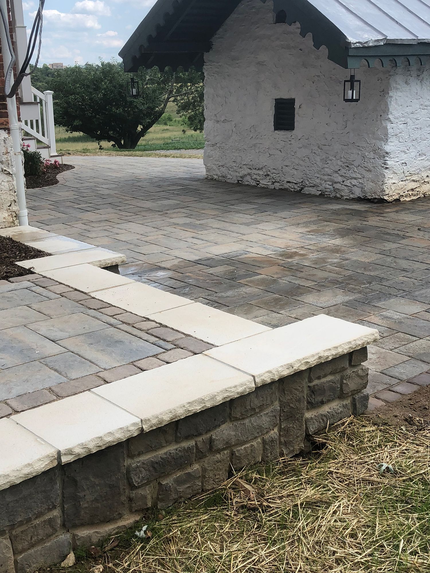 There is a brick wall in the foreground and a white building in the background.