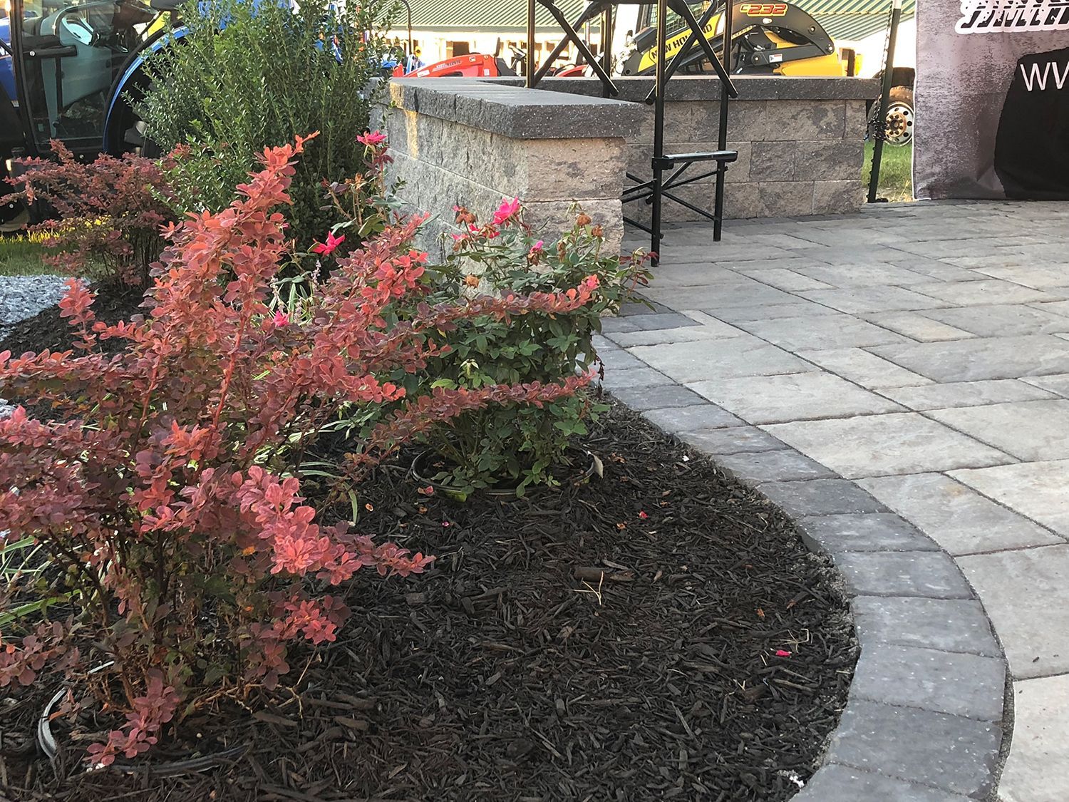 A patio with a fire pit and a bench in the background.