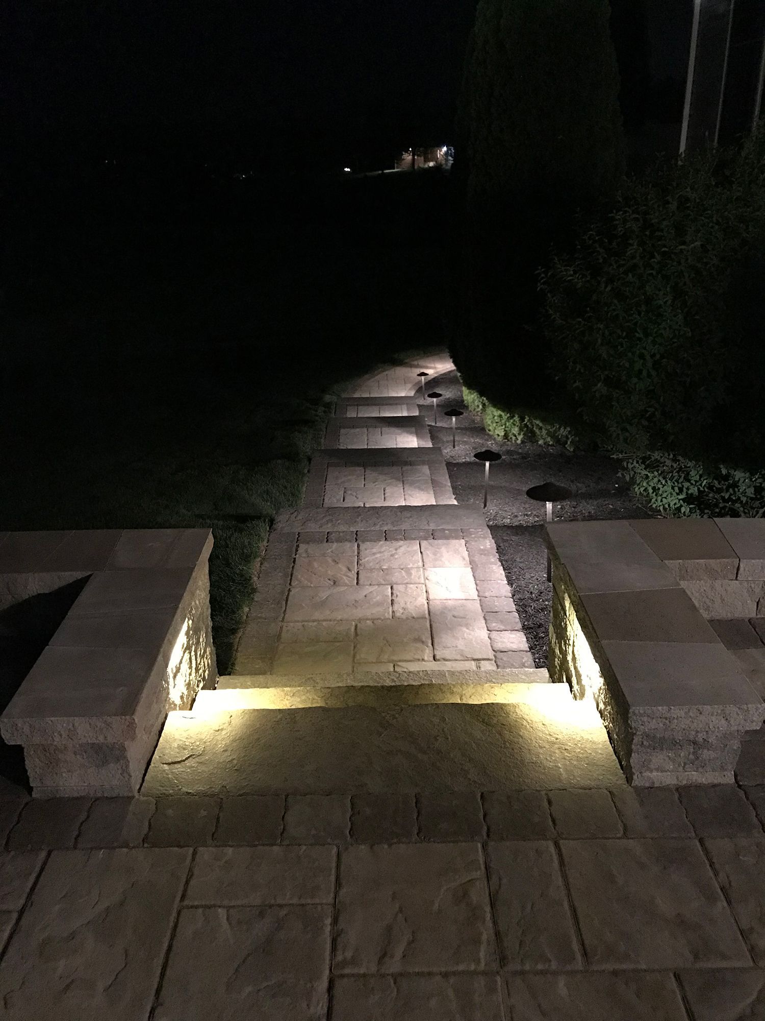 A stone walkway with lights on it at night.
